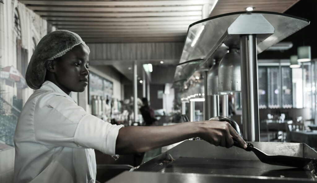 Food service staff member following hygiene procedures in a commercial food environment.